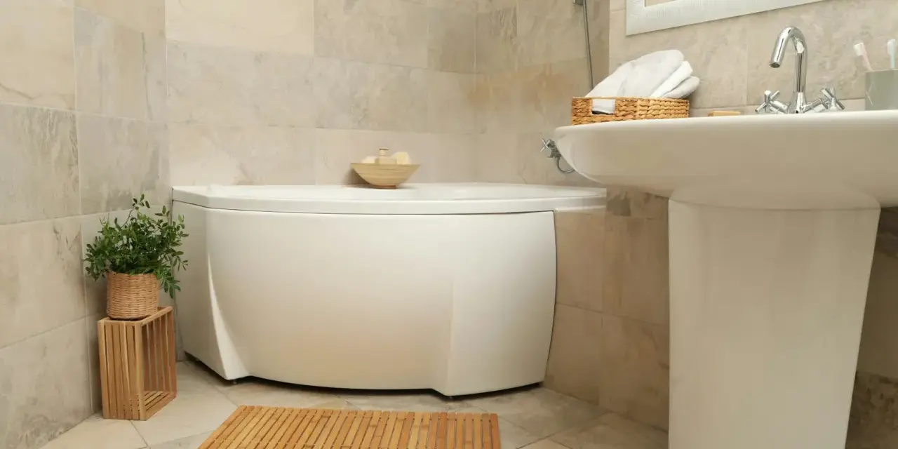 Ett badrum med hörnbadkar, handfat och en trämatta. Perfekt för liten toalett inspiration med naturliga material.