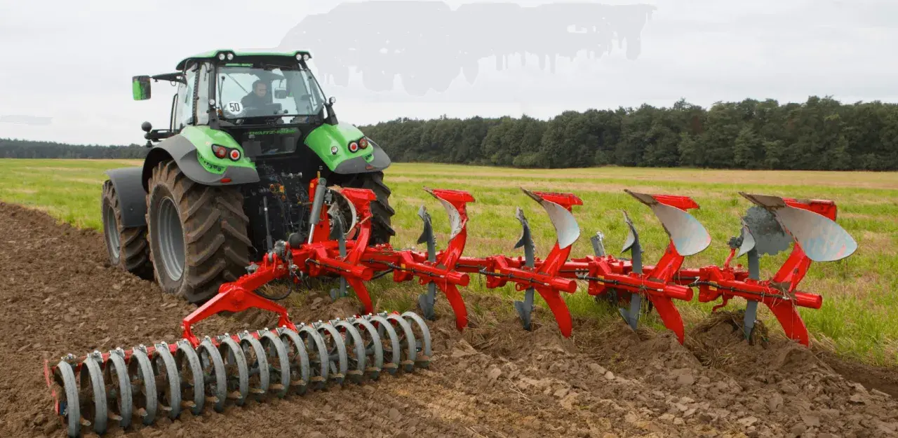 Zielony traktor z pługiem obrotowym pracuje na polu, przygotowując ziemię do siewu.