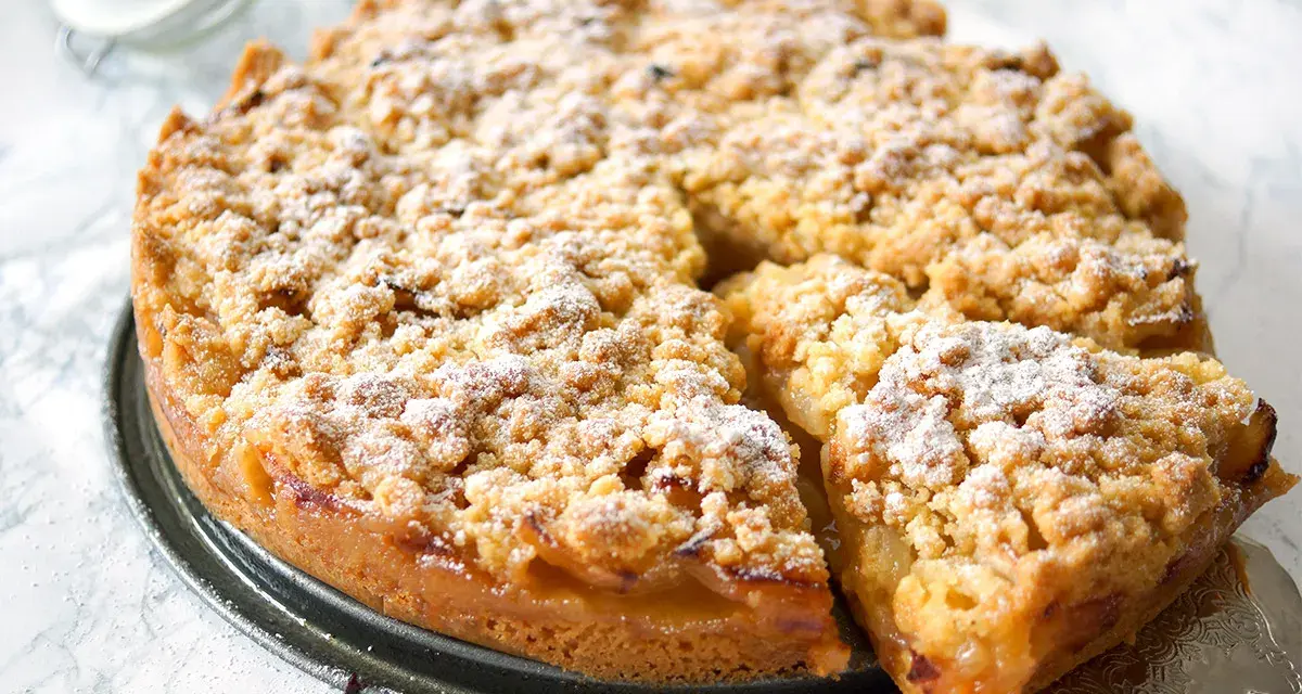Ein goldbrauner Apfelkuchen mit Streuseln, bestäubt mit Puderzucker. Dieses Apfelkuchen Rezept sieht köstlich aus!