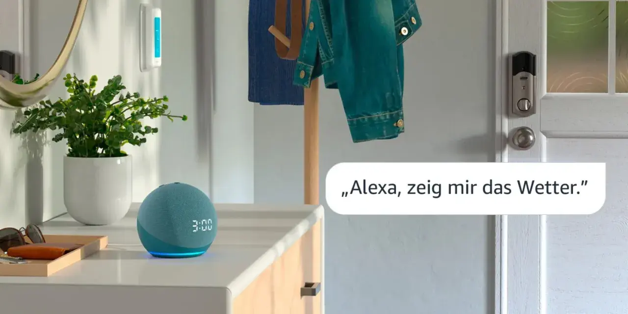 Alexa Routine erstellen: Ein blauer Echo Dot mit leuchtender Uhrzeit und eine Pflanze stehen auf einer Kommode. Eine Jacke hängt an einem Kleiderständer.