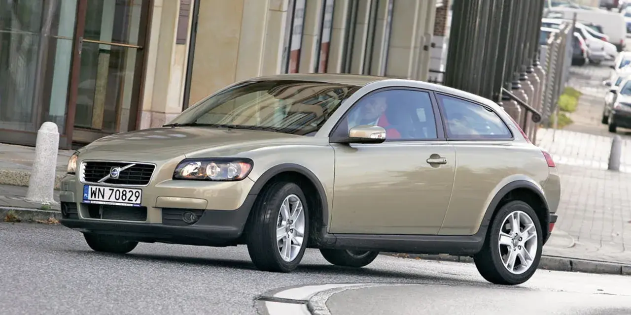 Złoty Volvo C30 z polskimi tablicami rejestracyjnymi WN 70829 jedzie po miejskiej ulicy.