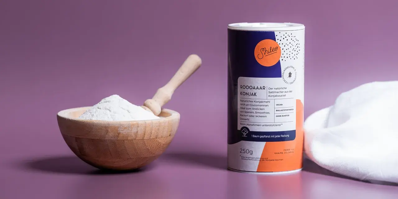 Holzschale mit weißem Konjakmehl und Löffel daneben, eine Dose mit der Aufschrift "Konjakmehl" und Produktinformationen.