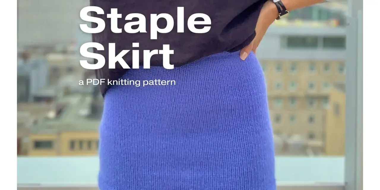 A person wearing a blue knitted skirt and a graphic t-shirt.