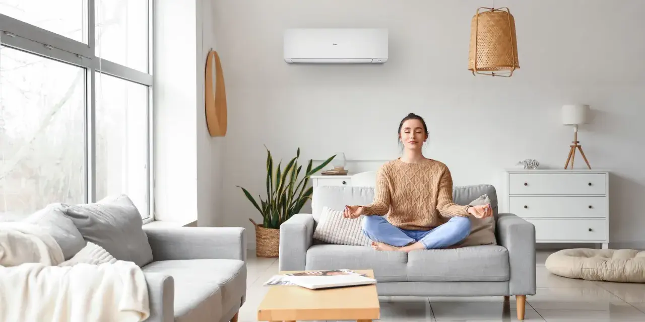 Donna medita in un soggiorno confortevole, con un condizionatore d'aria inverter che garantisce un clima ideale per il relax.