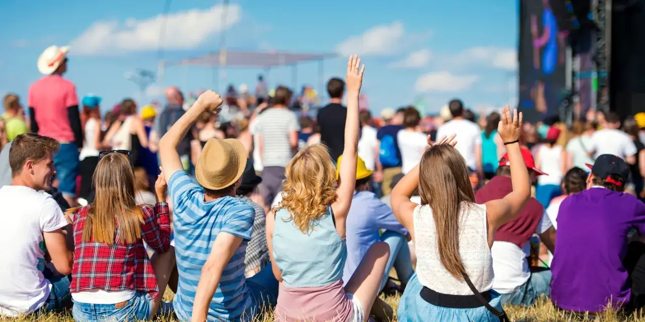 Widok zza pleców na tłum ludzi na jednym z największych festiwali muzycznych w Polsce. Słońce, niebo i dobra zabawa.