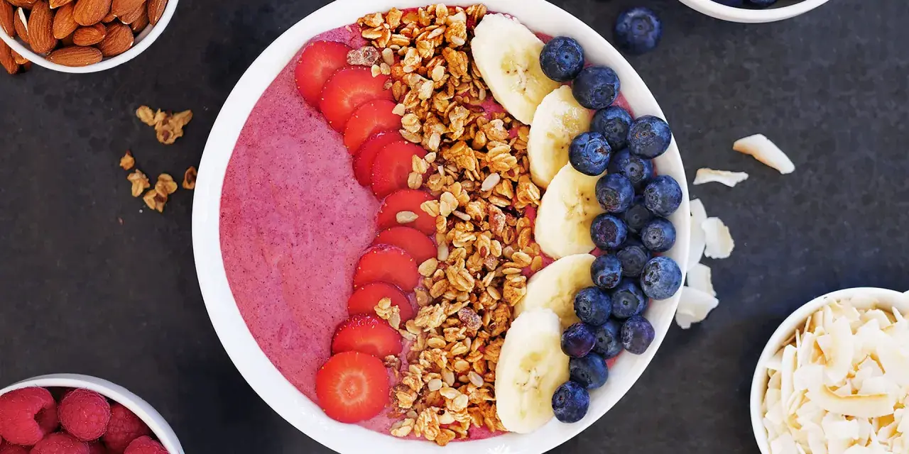 En färgglad acai bowl med jordgubbar, banan, blåbär och granola. Perfekt för en hälsosam frukost eller mellanmål.