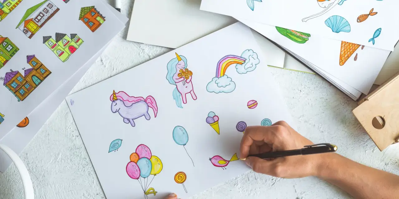 Une main dessine des licornes, des maisons et des bonbons, une scène parfaite pour une formation illustrateur jeunesse.