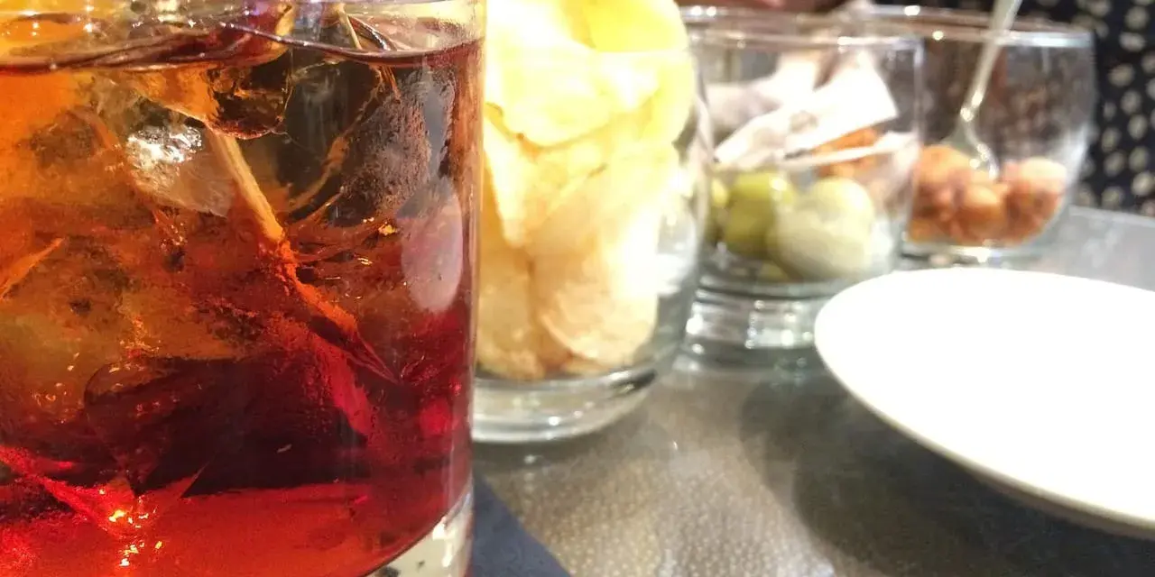 Orzeźwiający drink z rumem, lodem i cytryną, idealny do delektowania się w letni wieczór. Obok przekąski i chipsy.