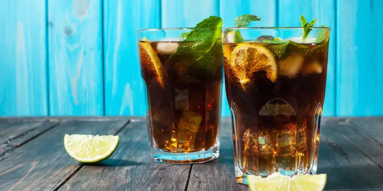 Dwa orzeźwiające drinki z rumem, lodem, limonką i miętą na drewnianym blacie. Idealny dobry drink z rumem na upalne dni.