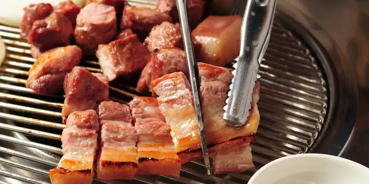 Pyszny boczek na grilla, idealny do marynaty. Kawałki mięsa skwierczą na ruszcie, gotowe do podania.