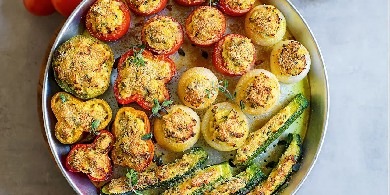 Vassoio di verdure ripiene al forno: pomodori, peperoni, cipolle e zucchine, dorate e profumate.
