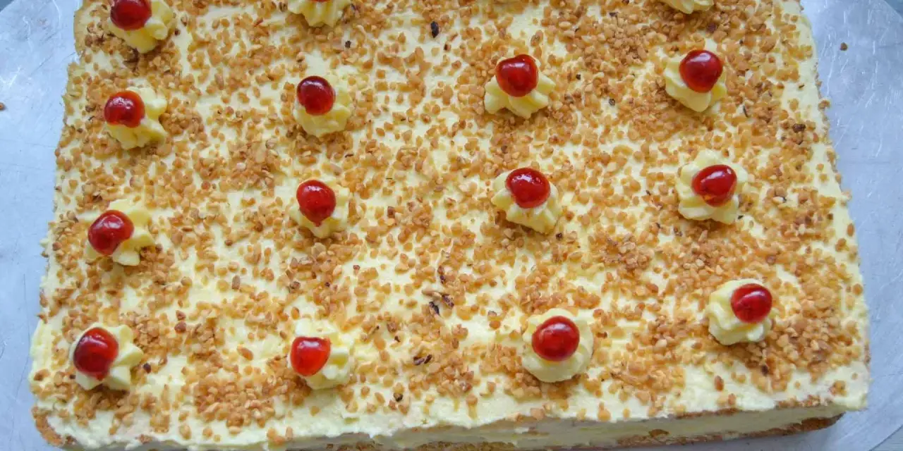Rechteckiger Frankfurter Kranz Kuchen, bestreut mit gehackten Nüssen und verziert mit Sahnetuffs und Kirschen. Sally liebt diese Schnitten!