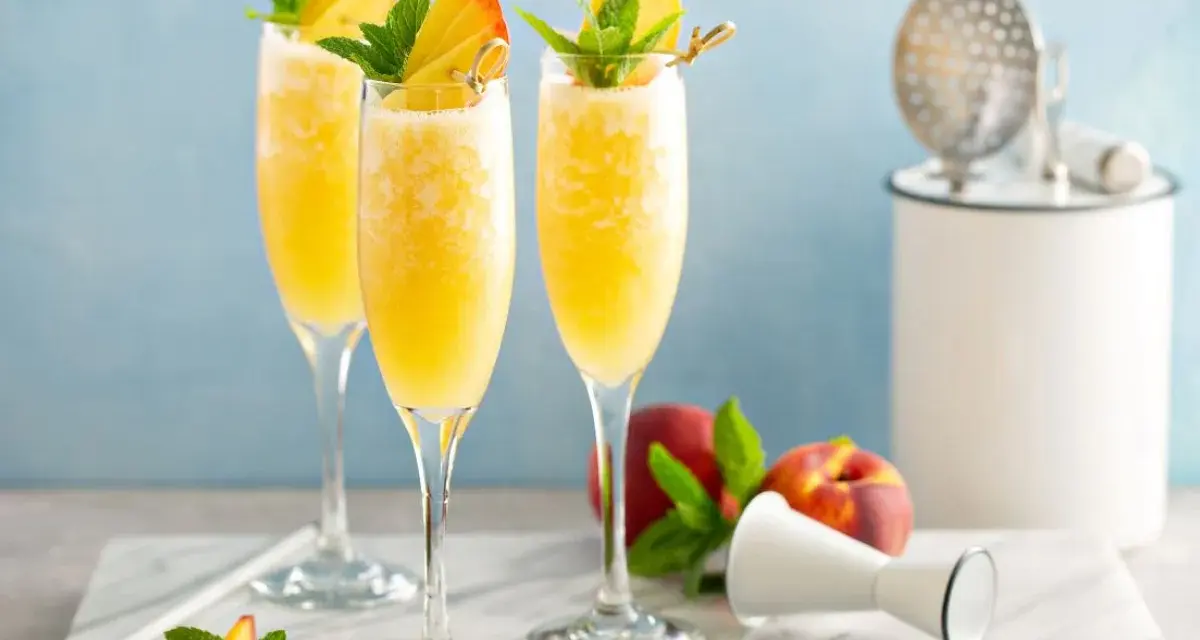 Orzeźwiający drink z prosecco i sokiem pomarańczowym, udekorowany brzoskwinią i miętą. Idealny na letnie popołudnie.