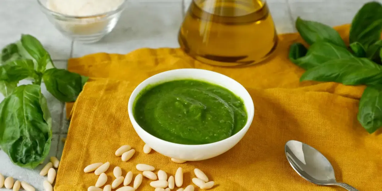 Una ciotola di pesto fresco, pinoli, basilico, parmigiano e olio d'oliva, ingredienti perfetti per una deliziosa pasta al pesto.