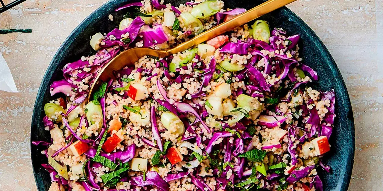 En färgstark couscous sallad med rödkål, äpple och färska örter. En gyllene sked vilar i den fräscha salladen.