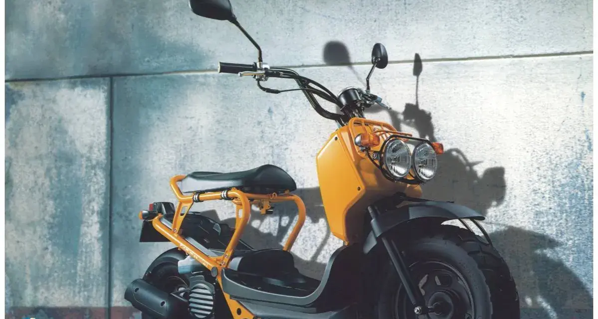Pomarańczowy Honda Zoomer z podwójnymi reflektorami i charakterystyczną ramą, gotowy do miejskich przygód.