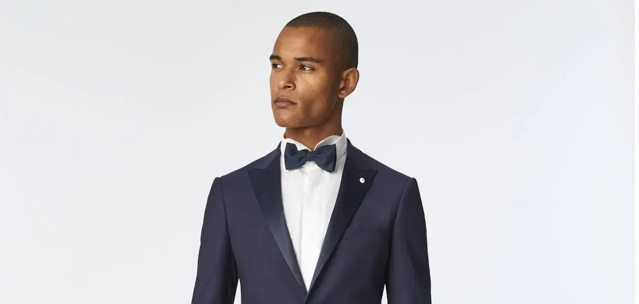 Uomo con abito nero e cravatta blu, pronto per un evento elegante.