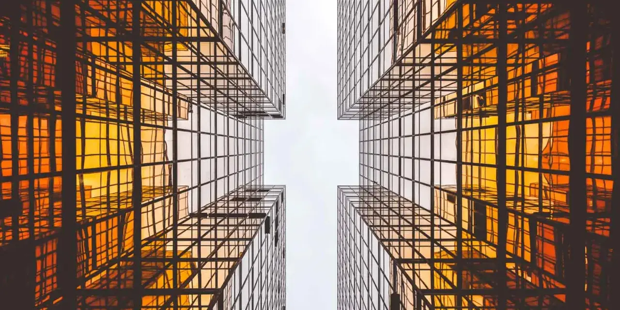 Looking up between four golden glass buildings, the architecture forms a cross shape, resembling a modern church.
