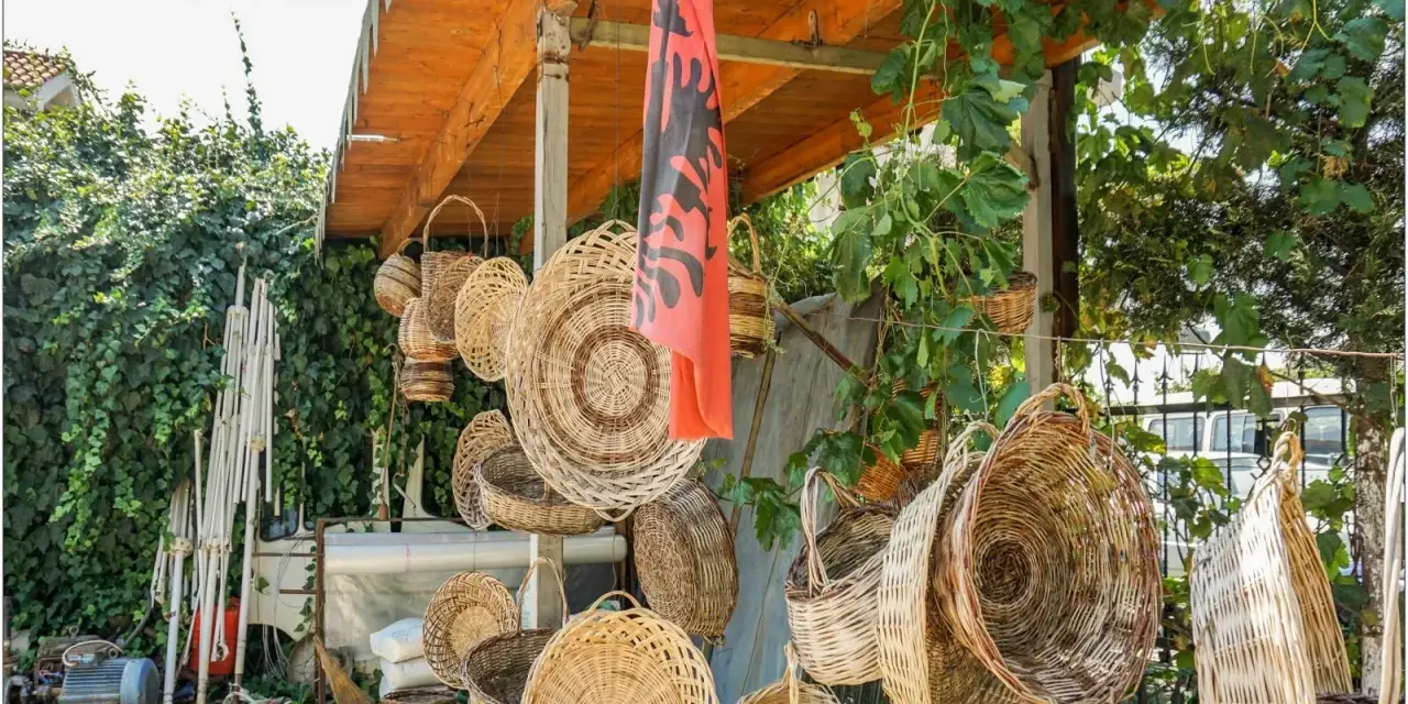 Wiele koszy z wikliny wisi pod zadaszeniem, obok albańskiej flagi. Czy Albania jest bezpieczna dla kobiet? Tak, to piękny kraj.