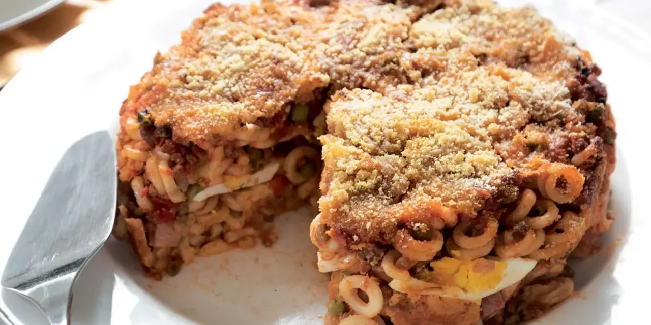 Un invitante anelletti al forno, con strati di pasta, sugo, piselli e uova sode, ricoperto da pangrattato dorato.