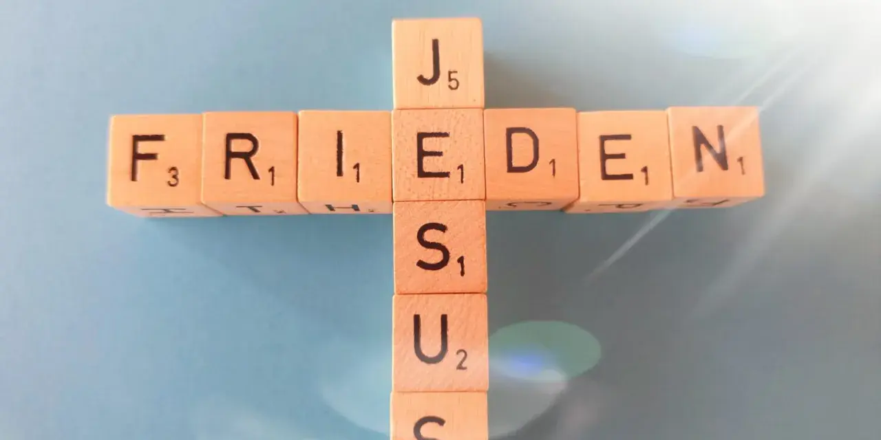 Holzbuchstaben bilden ein Kreuz mit den Wörtern "FRIEDEN" und "JESUS". Wie in Jesaja 43,2 versprochen, bringt Jesus Frieden.