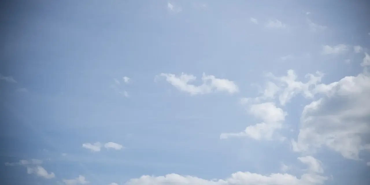 Jasne niebo z chmurami, efekt winietowania przyciemnia brzegi kadru, tworząc wrażenie głębi.