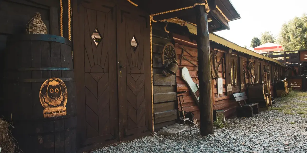 Drewniana chata wuja Toma z beczką i ozdobami.