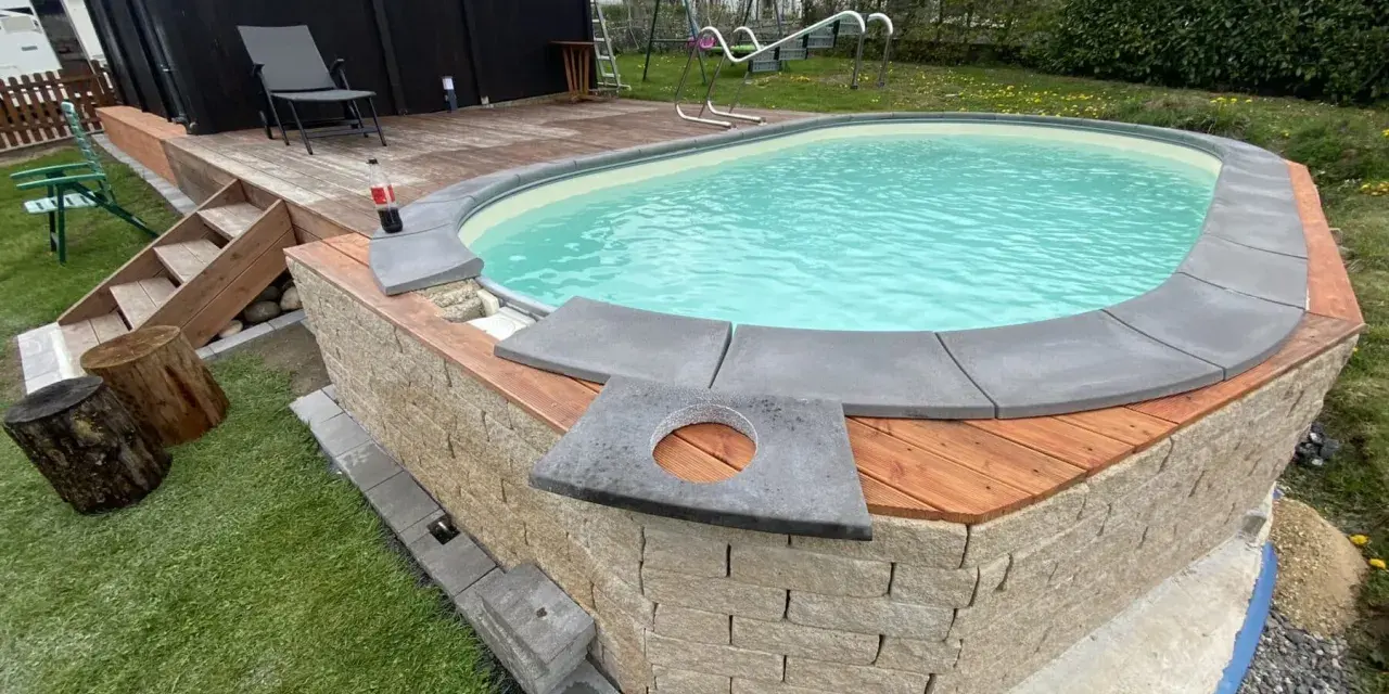 Ein Pool mit selbstgemachten Randsteinen, umgeben von Holz und Naturstein.