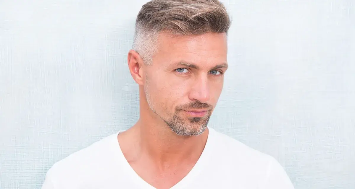 Hombre con barba corta y cabello peinado, luciendo un estilo moderno. Decidió dejarse perilla para un look más definido.
