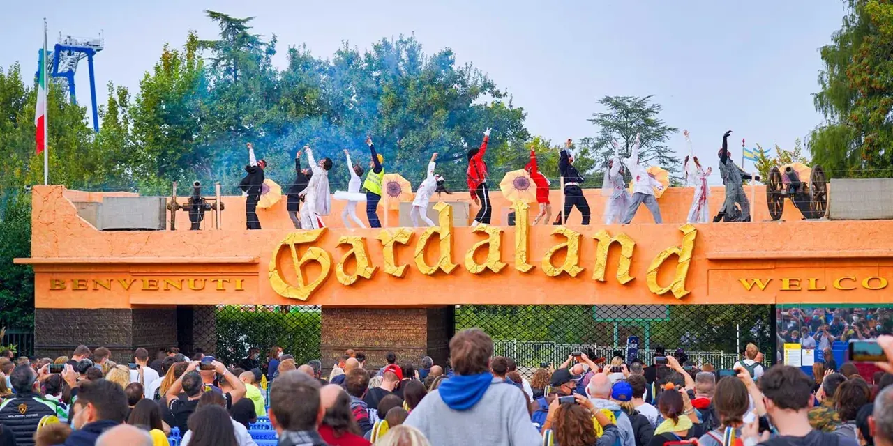 L'emozione di arrivare da Verona a Gardaland: artisti danzano sull'ingresso mentre la folla attende l'avventura.