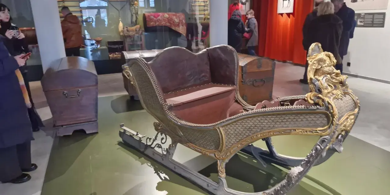 Złota, zdobiona sanie w muzeum tradycji szlacheckiej w Waplewie Wielkim. Obok skrzynie.