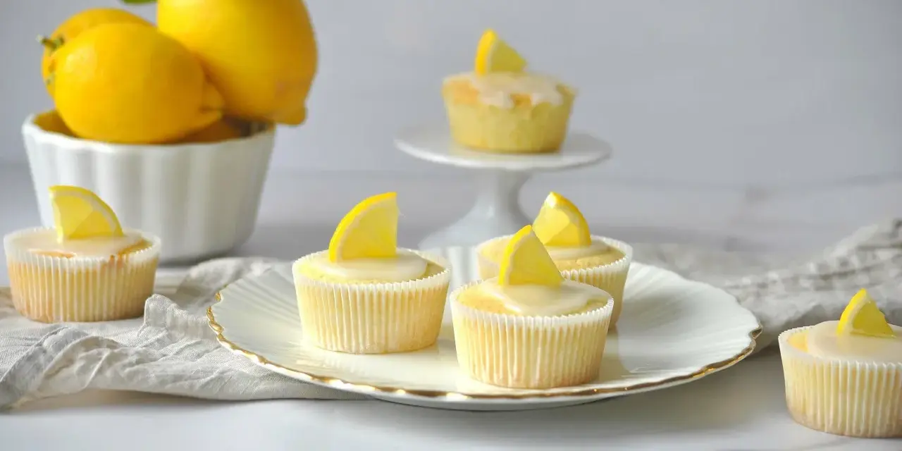 Erfrischende Zitronenmuffins mit Zuckerguss und Zitronenspalten, inspiriert von einem einfachen zitronenmuffins rezept.