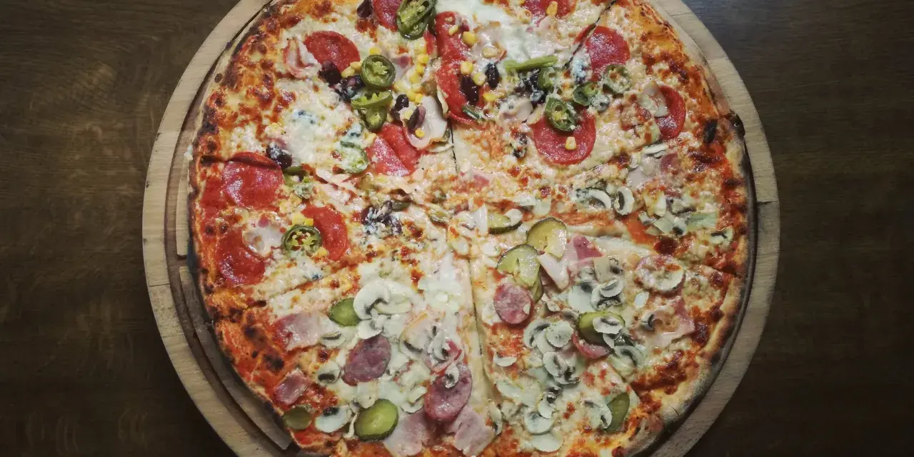Pizza 32 cm z różnymi dodatkami: salami, kukurydza, jalapeno, pieczarki, ogórek, szynka.
