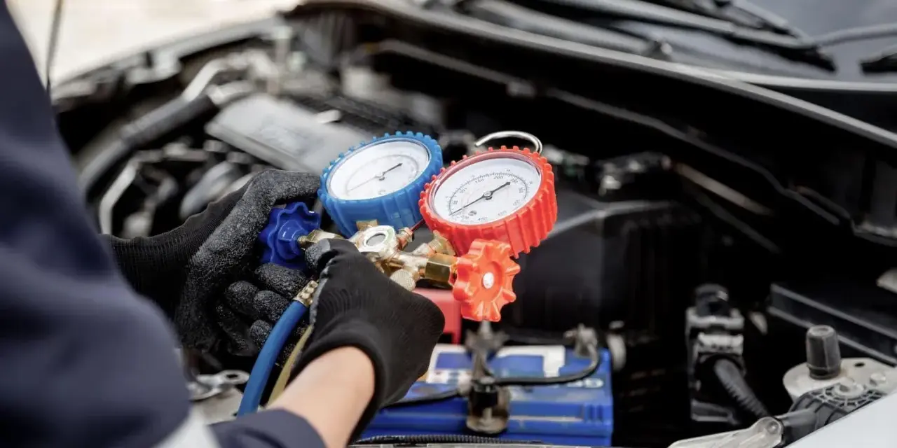Mechanic checks car AC pressure with gauges. This helps determine how much to fix AC in car.