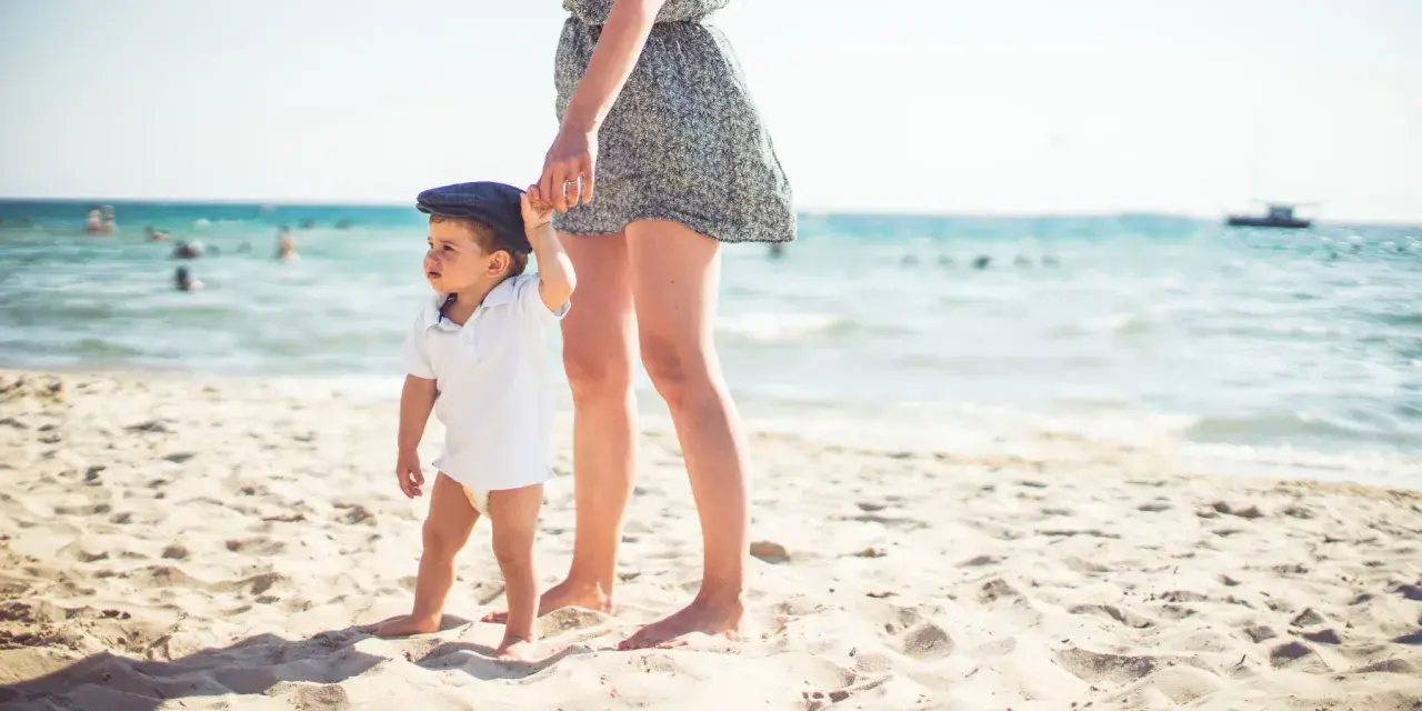 Mama i dziecko na plaży, idealne miejsce, by zapytać, gdzie lecieć w kwietniu. Słońce, piasek i morze.
