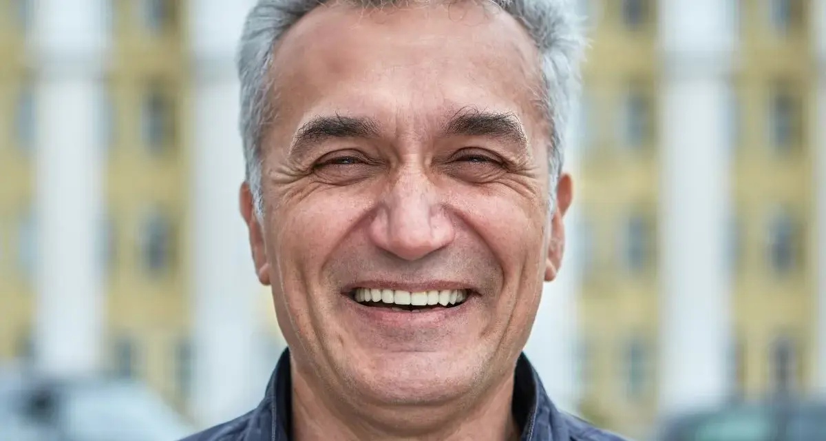 Uśmiechnięty mężczyzna z siwymi włosami, który wygląda jak typowy boomer. Co to znaczy? To ktoś z pokolenia wyżu demograficznego, często kojarzony z pewnymi wartościami i stylem życia.