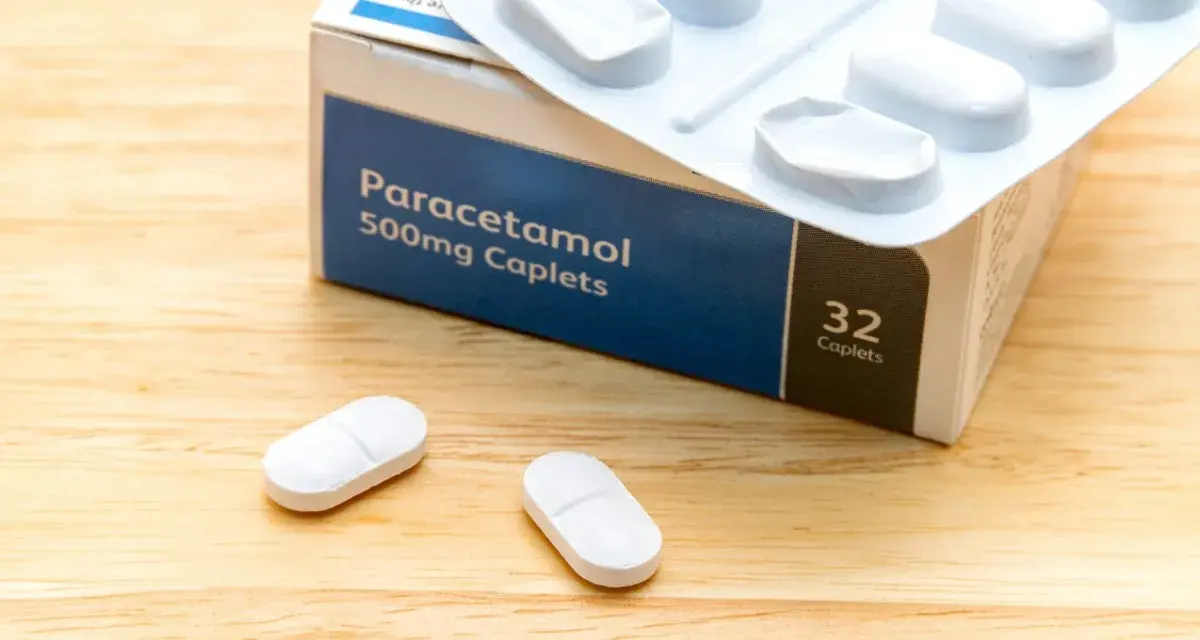Opakowanie paracetamolu 500mg i dwie tabletki na drewnianym tle. Szybka ulga w bólu zęba.