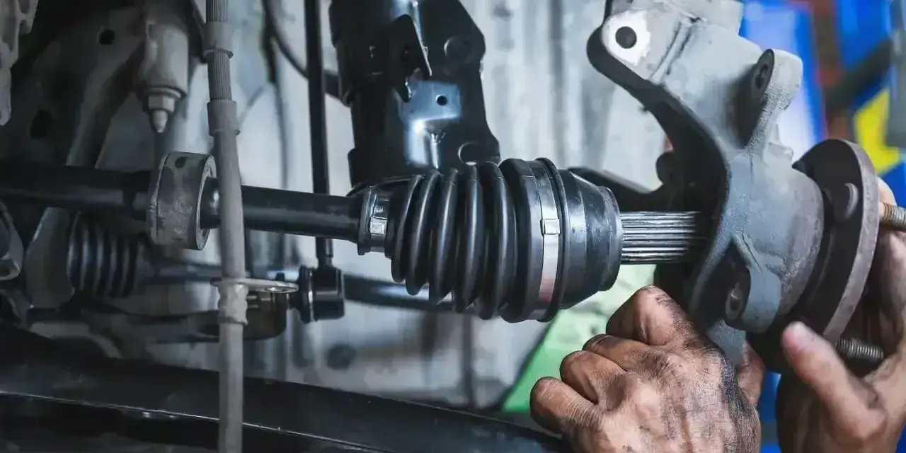 Mechanik wymienia przegub w samochodzie. Dowiedz się, ile kosztuje wymiana przegubu i jakie są objawy jego zużycia.