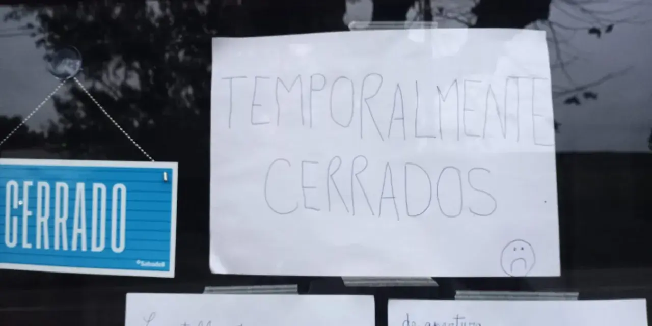 Cartel de "CERRADO" y otro escrito "TEMPORALMENTE CERRADOS" en la ventana de un bar restaurante.