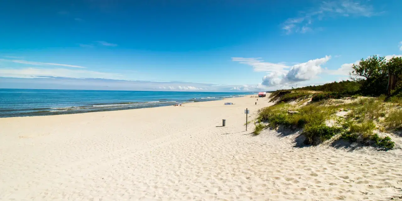 Piękna, piaszczysta plaża na Mierzei Wiślanej. Błękitne niebo i spokojne morze zapraszają do wypoczynku.