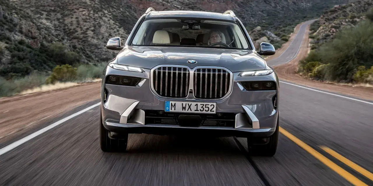 Szary BMW X7M pędzi krętą drogą przez pustynny krajobraz.