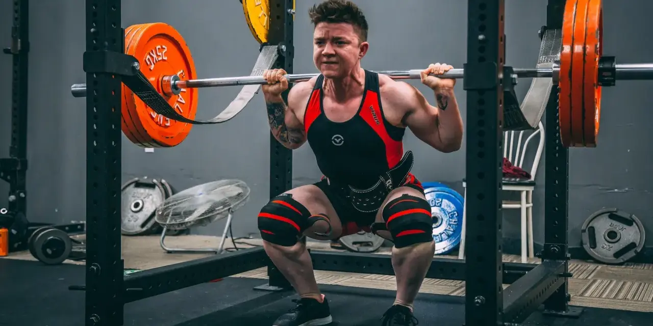 En person utför squats med vikt i ett gym.