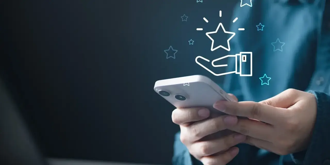 Dłoń trzyma smartfon, a nad nim świecą gwiazdki. To wizualizacja tego, czym jest cashback – zwrot części pieniędzy za zakupy.