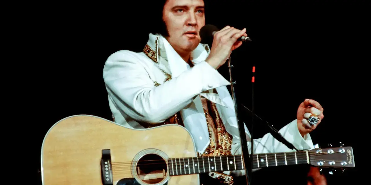 Elvis Presley singt mit Gitarre und Mikrofon, ein Bild, das sein immenses Vermögen symbolisiert.