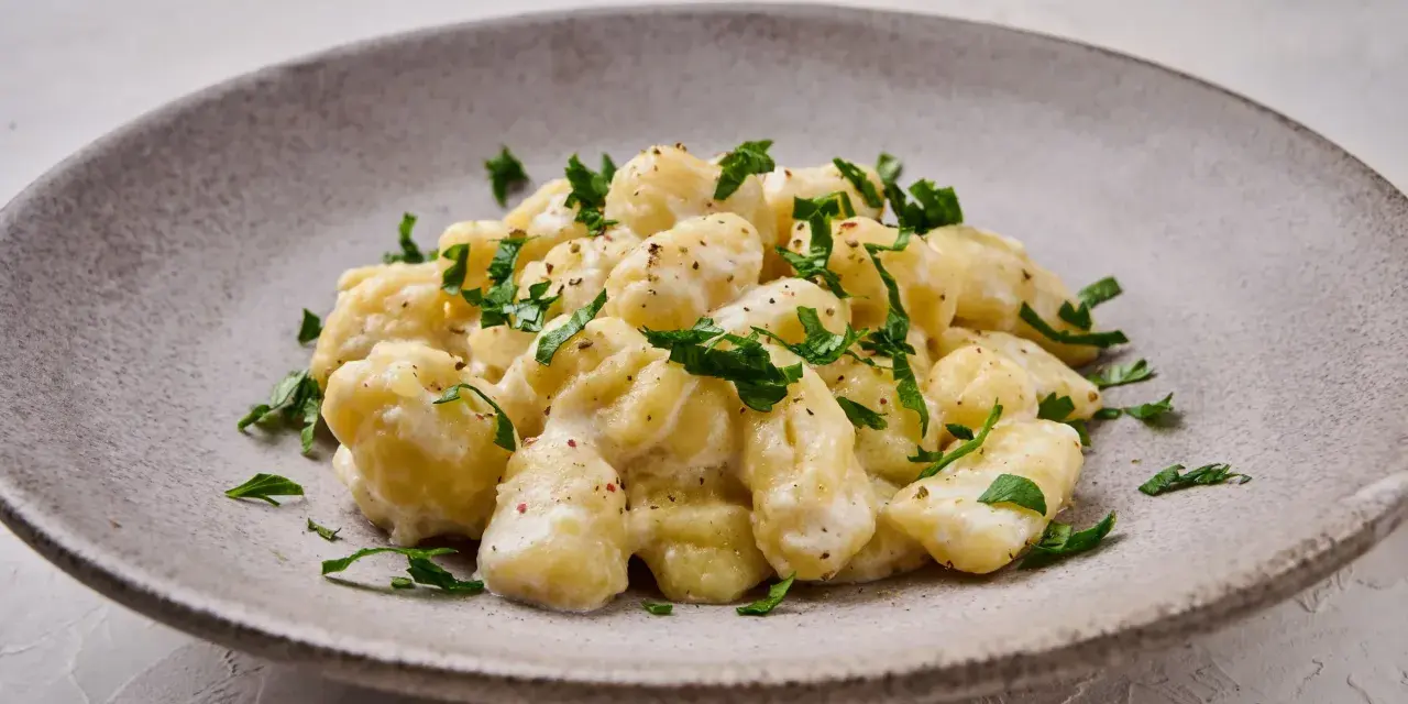 Pyszne gnocchi z kremowym sosem, posypane świeżą natką pietruszki. Idealne danie dla każdego miłośnika włoskiej kuchni.