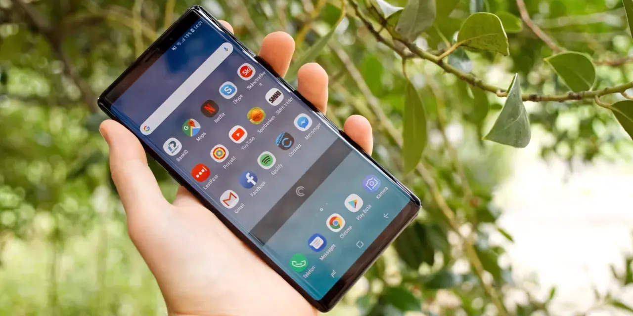 En hand håller en Samsung Galaxy Note 9 med många appar på skärmen, bland annat BankID och Spotify.