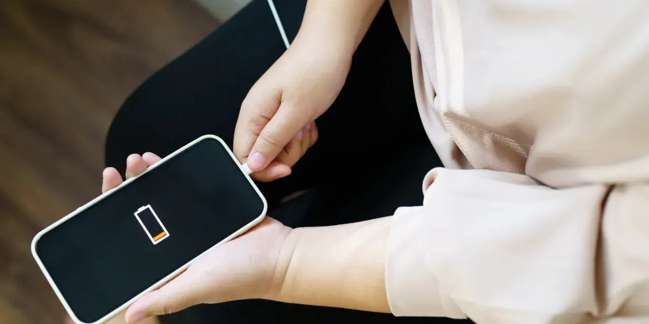 En person kopplar in sin iPhone som drar mycket batteri. Batteriikonen visar låg laddning.