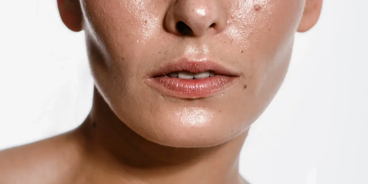 Primo piano del viso lucido, con pori visibili e qualche imperfezione. Scopri come eliminare il sebo in eccesso dal viso per una pelle radiosa.