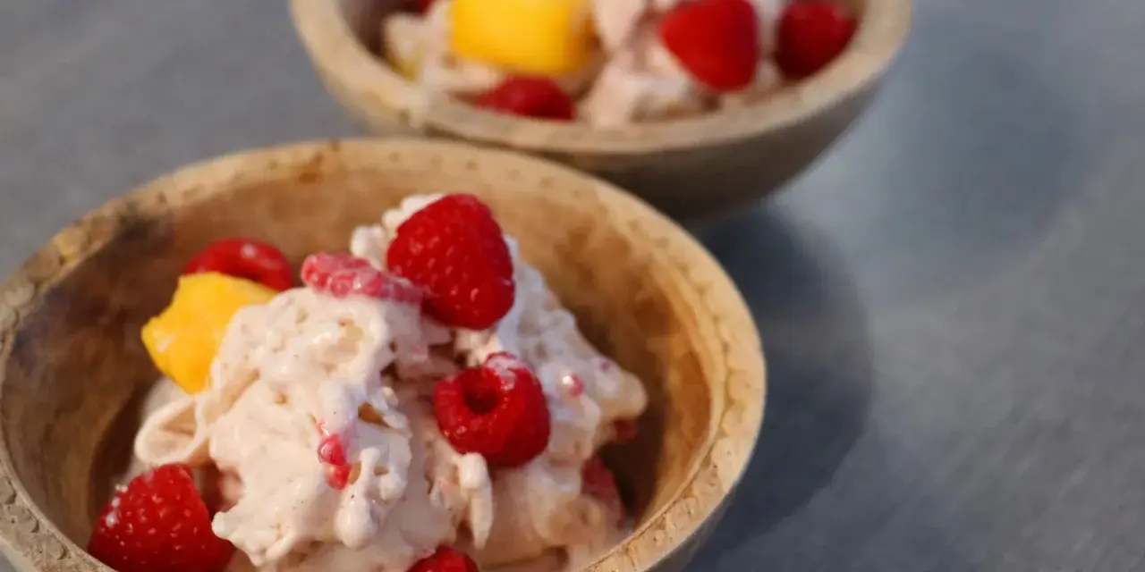 Två skålar med krämig proteinglass, toppad med hallon och mangobitar. Ett perfekt recept för en hälsosam dessert.