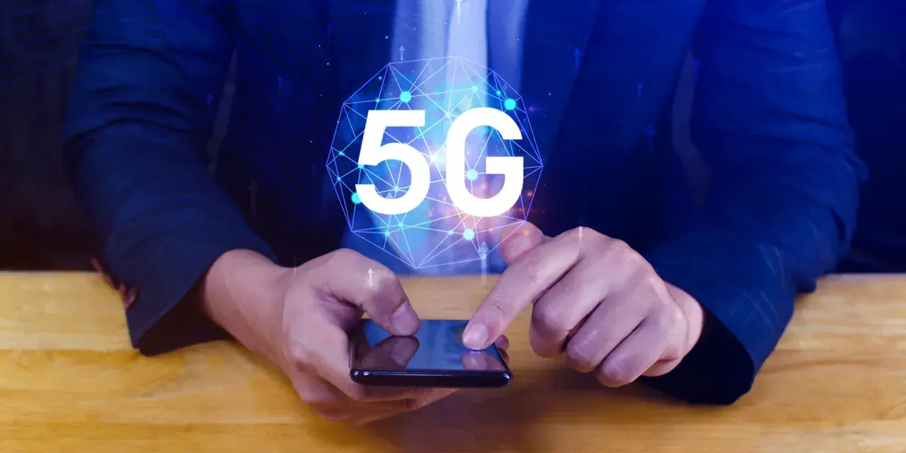 Dłoń na smartfonie, symbol 5G nad nim. Dowiedz się, jak wyłączyć 5G w telefonie, aby kontrolować połączenie.